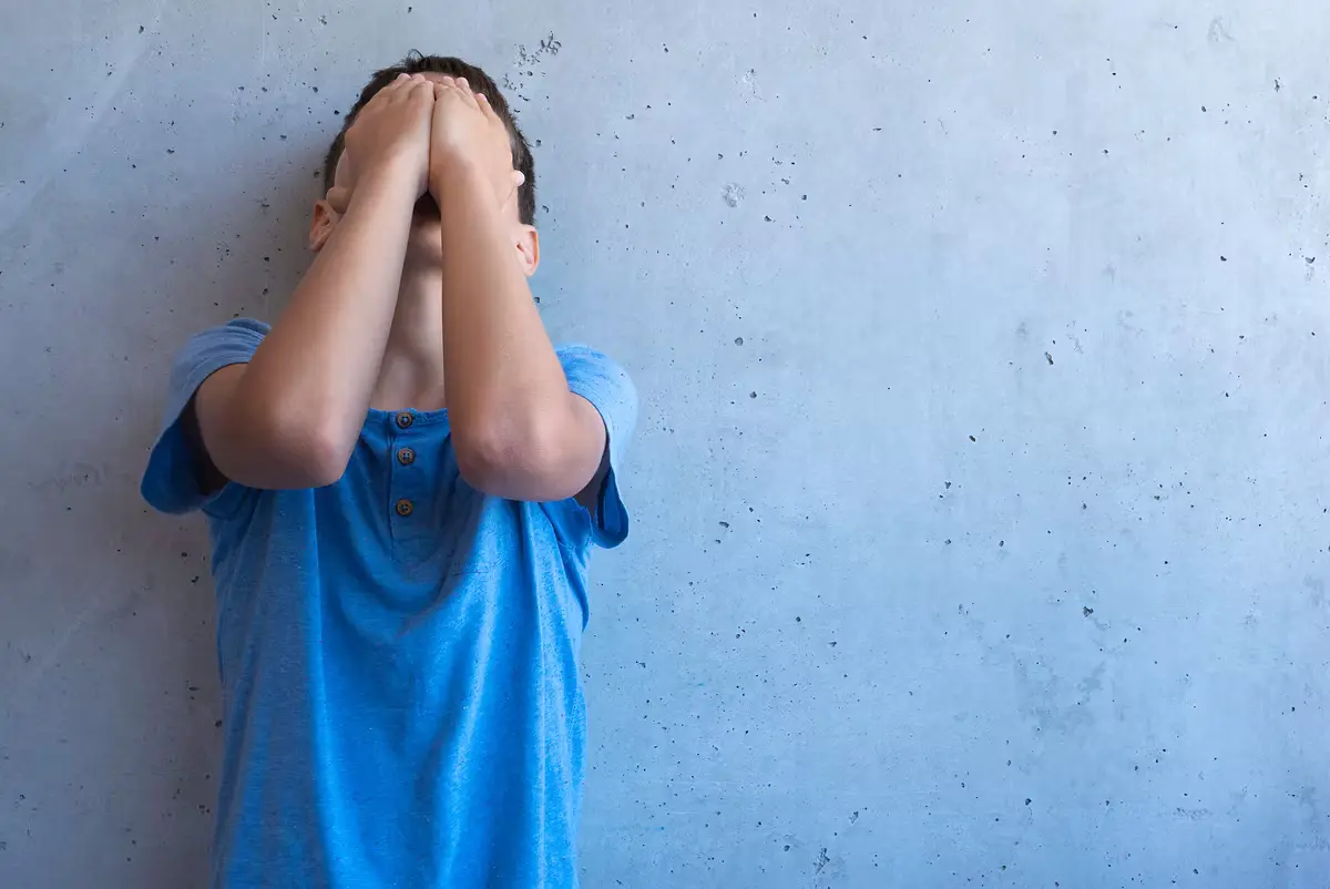 Upset sad boy stand alone and leaning on