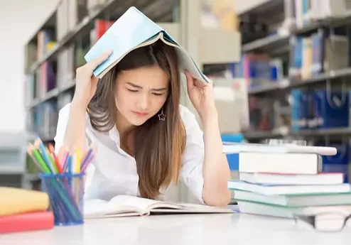 Worried Student Looking At Books On Desk